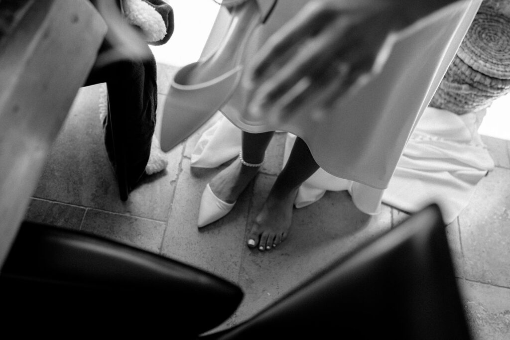 A bride preparing to wear her elegant shoes at a northern California private estate wedding, with a glimpse of her pedicured foot.