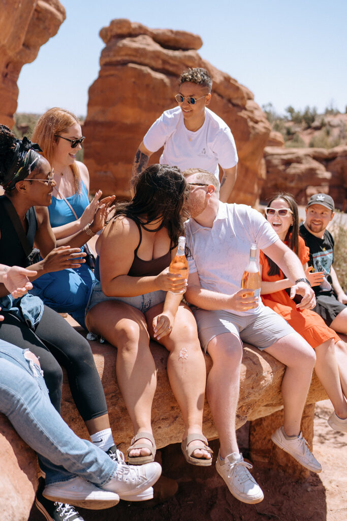 Couple kiss surrounded by friends after proposal at Garden of the Gods in Colorado Springs | Engagement photography