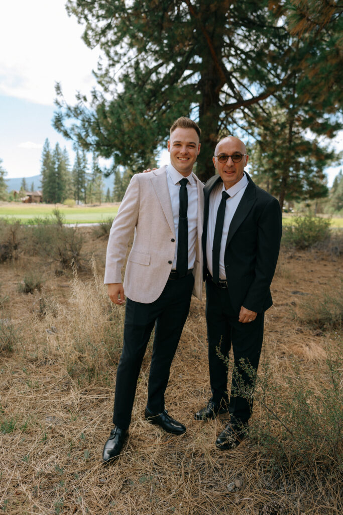 Groom posing with a friend in front of a pine backdrop, moments before their rustic wedding ceremony at Tahoe Mountain Club.