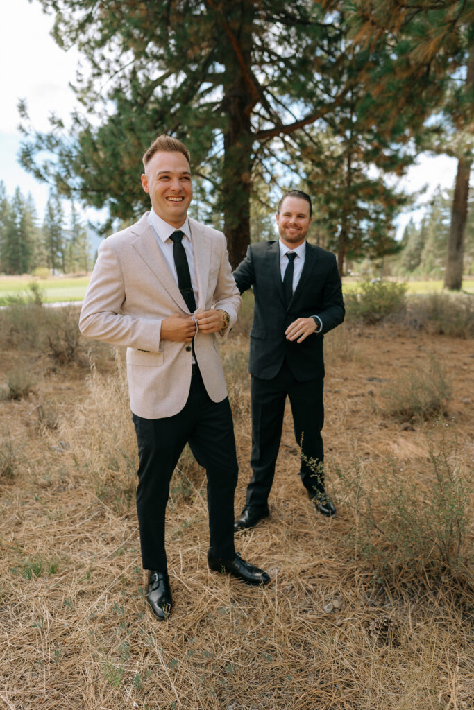 Groom smiling as a groomsman stands by in a pine-filled meadow, capturing the relaxed vibe of a mountain wedding near Lake Tahoe.