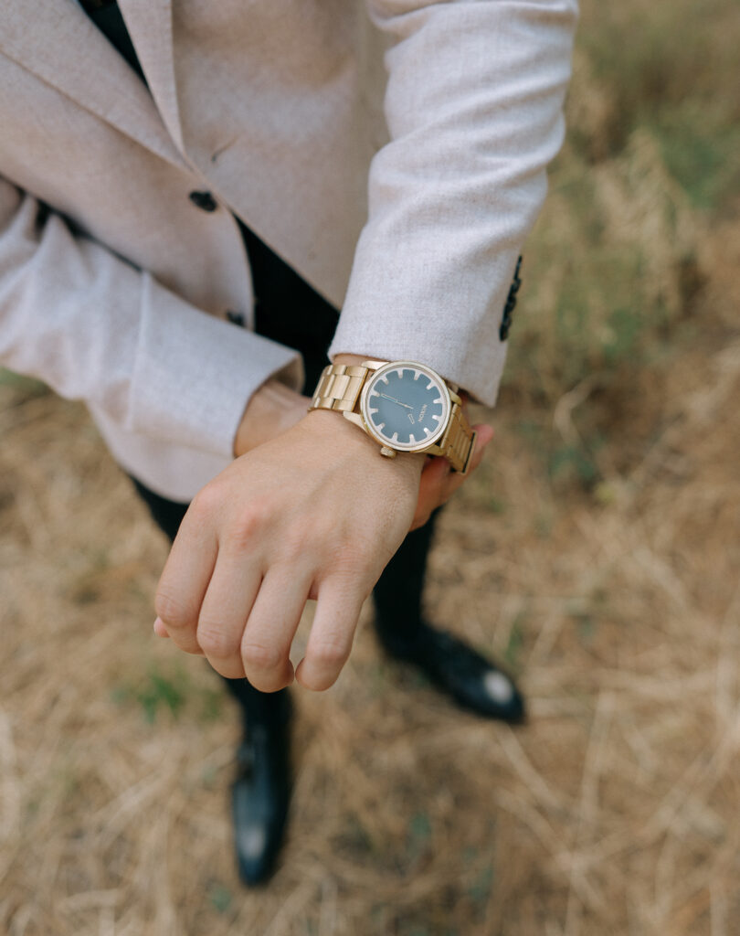 Close-up of the groom’s gold watch against a beige blazer, set in the rustic elegance of a Tahoe Mountain Club wedding.