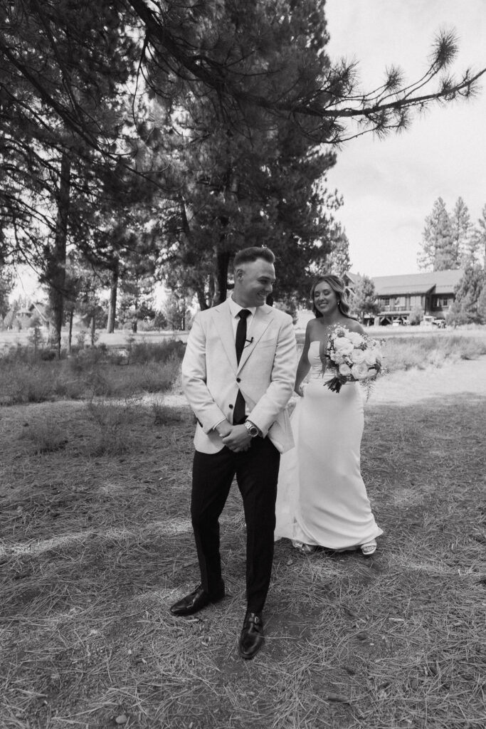 Black-and-white shot of the bride surprising the groom in a forest clearing, capturing a playful pre-ceremony moment at their Tahoe Mountain Club wedding.