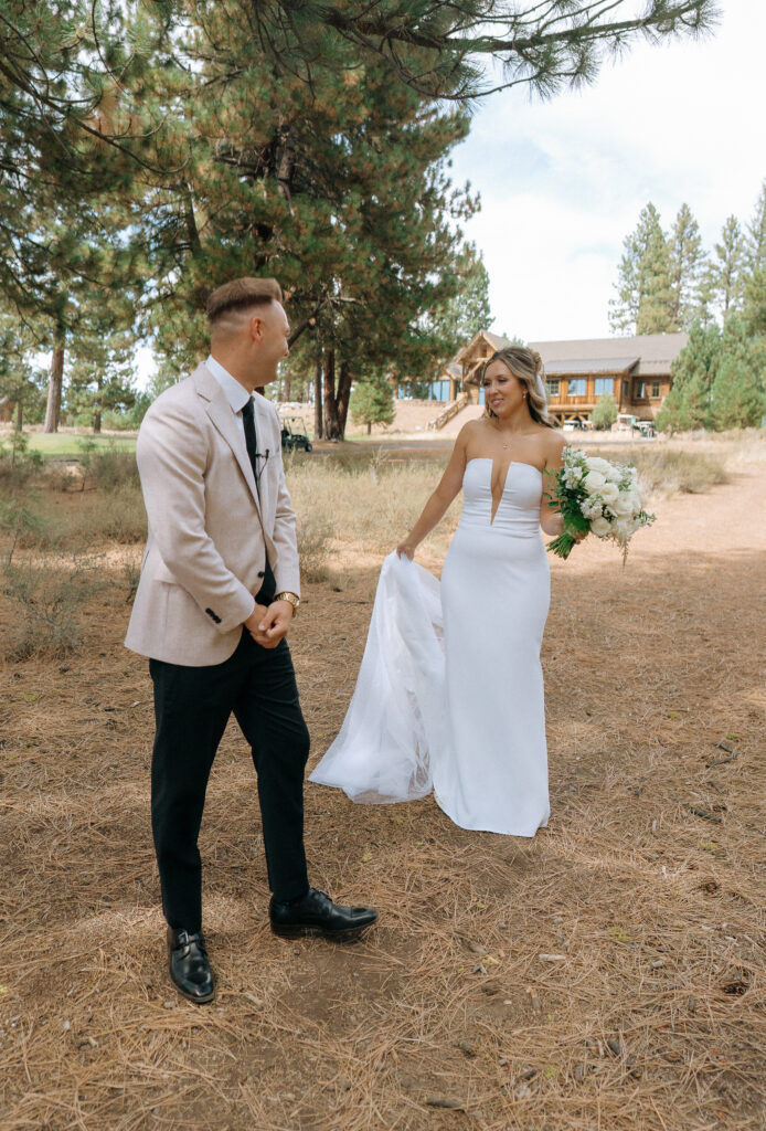 Bride in a strapless white gown walking toward the groom under tall pines, embracing the outdoorsy charm of a Truckee wedding.