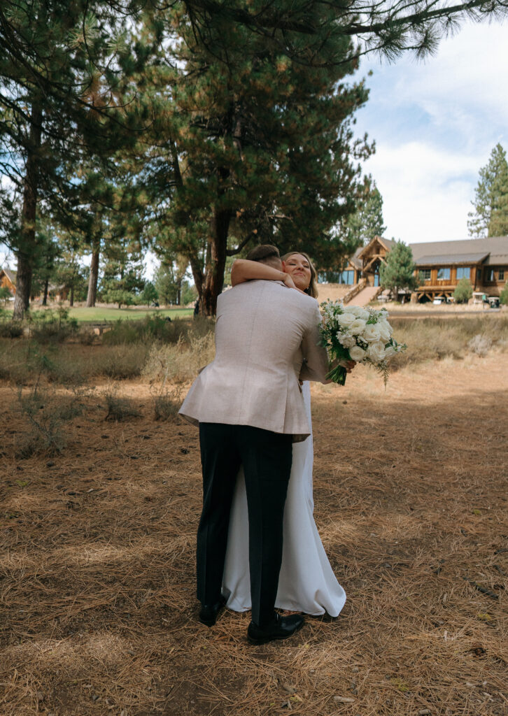 Bride and groom embracing beneath towering pines, celebrating their special day in Truckee’s breathtaking mountain setting.