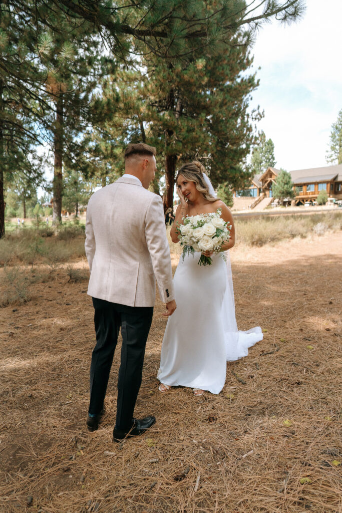 Groom and bride share a lighthearted moment in a pine forest, highlighting the scenic backdrop of their Tahoe Mountain Club wedding day.