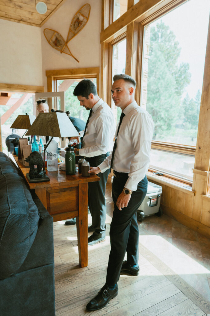 Groom and groomsmen gathering around a wooden bar in a light-filled lodge, getting ready for a Tahoe Mountain Club wedding in Truckee.