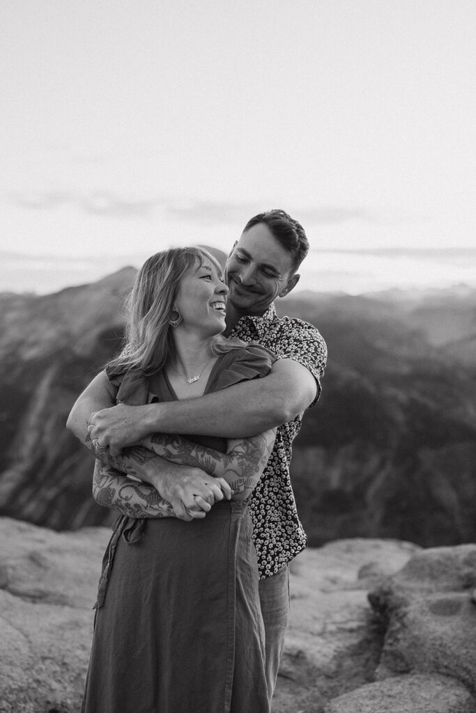 A black and white shot of a couple embracing as they laugh, documented by a Yosemite photographer.