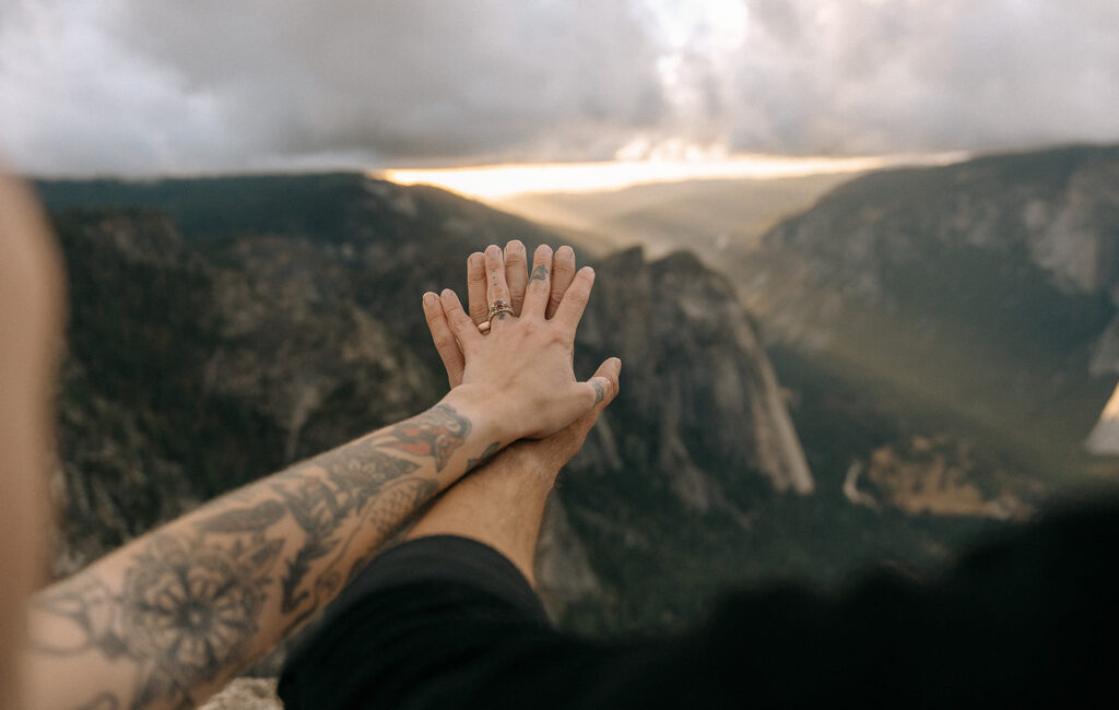 A couple’s hands reaching out over Yosemite Valley from Taft Point at sunset, documented by a Yosemite photographer.